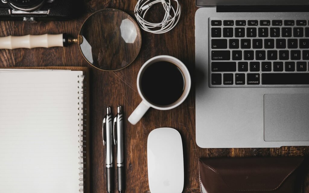 Top-down view of a desk with a laptop, notebook and coffee