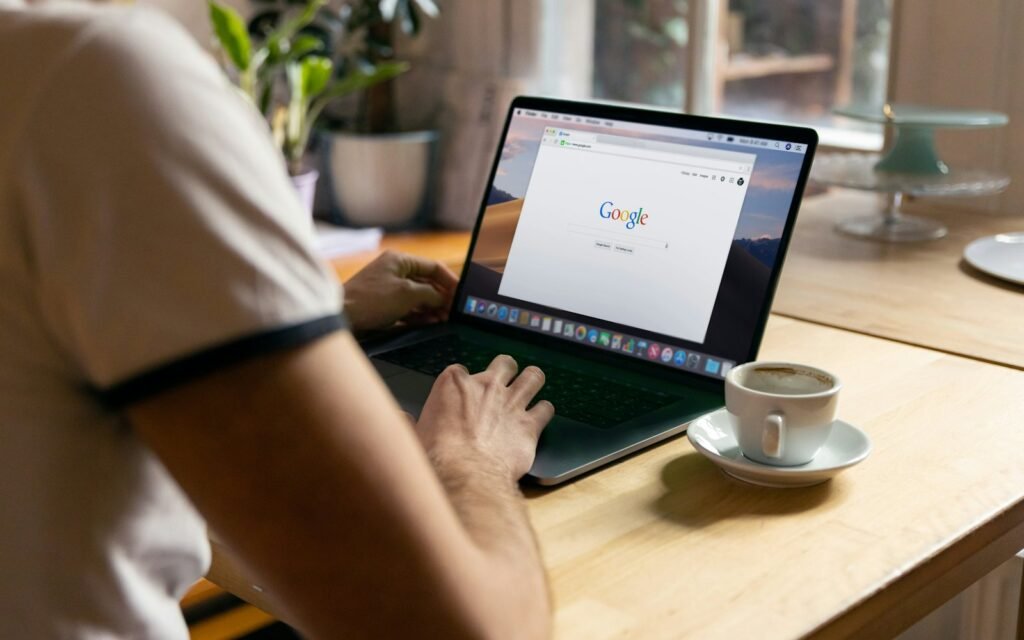 Person searching Google on a laptop with a coffee