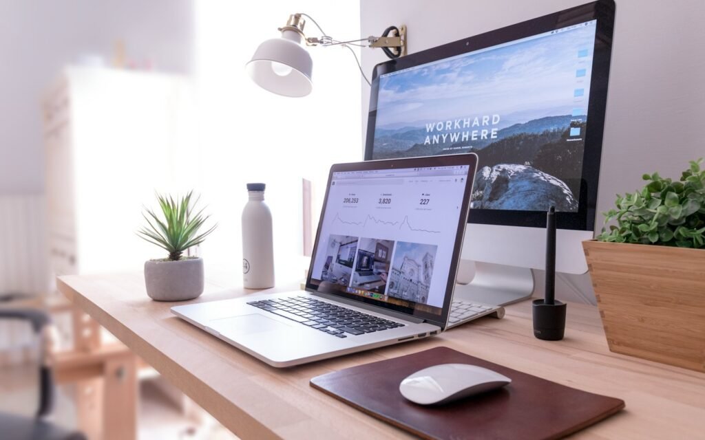 Desk with a desktop computer and laptop showing a website design